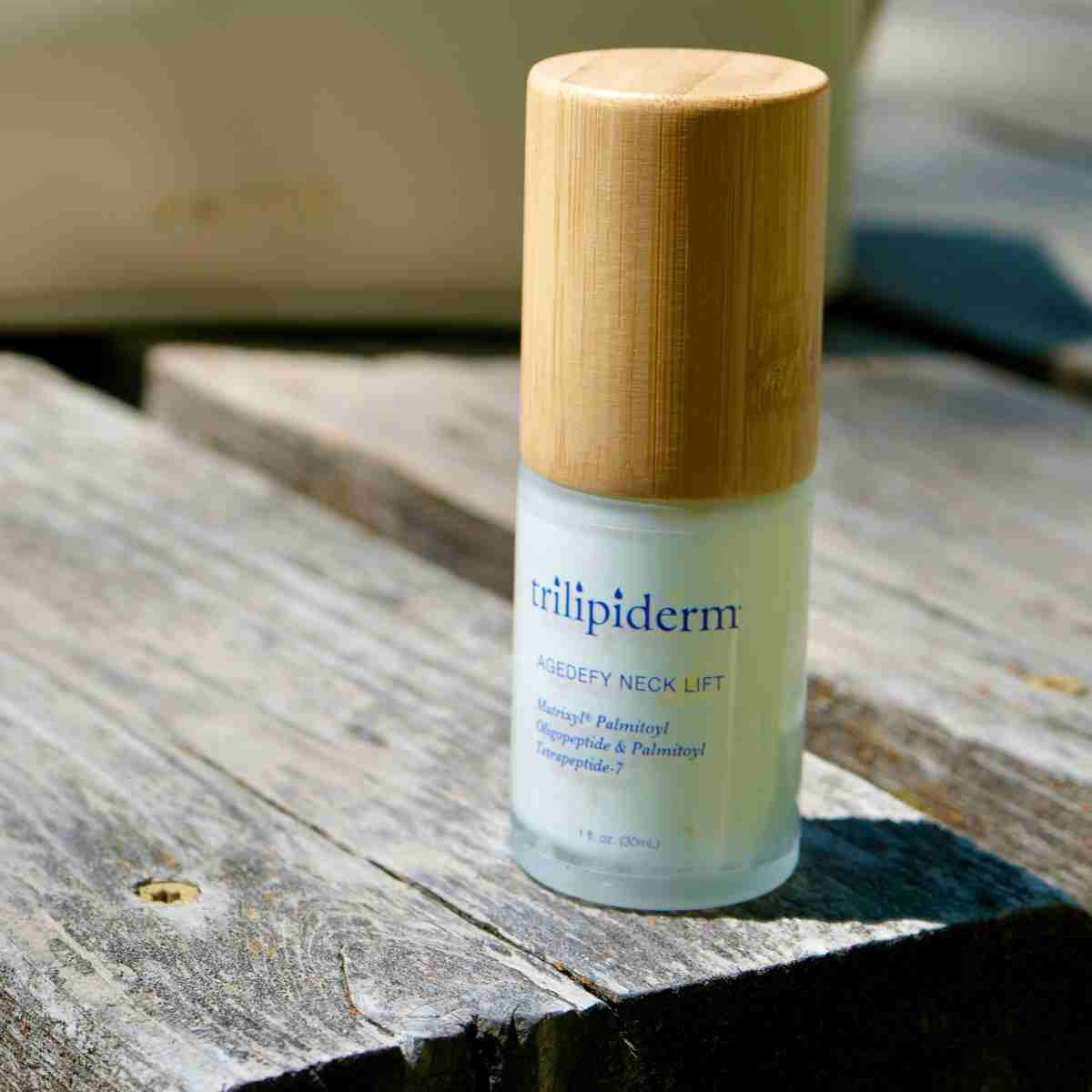Trillipiderm neck lift cream bottle with wooden cap on a wooden surface