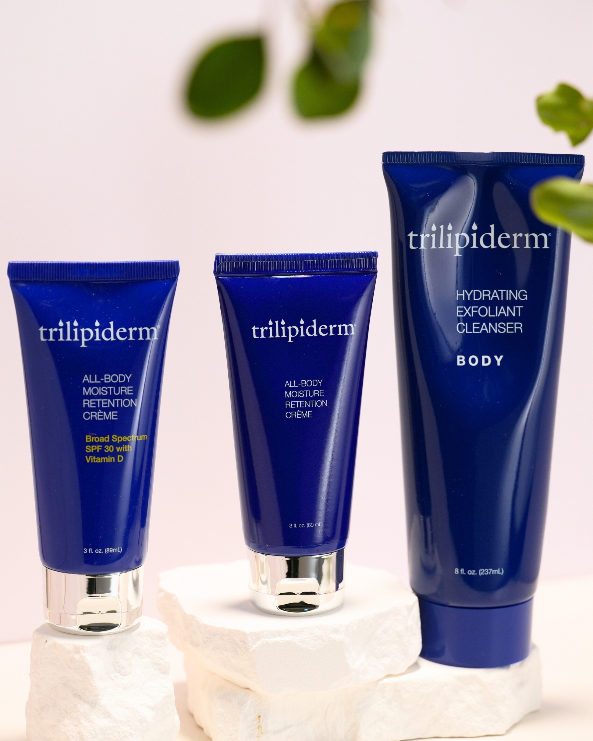 Trilipiderm skincare products on a light background with green leaves.