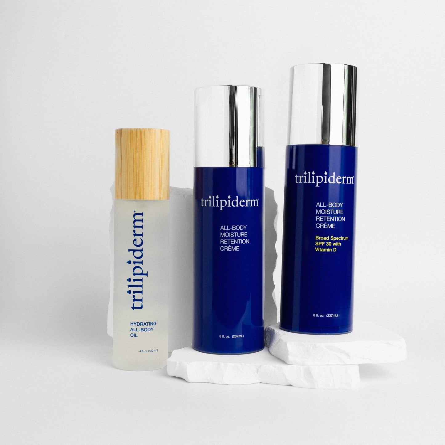 Trilipiderm skincare products on a white background and white rock