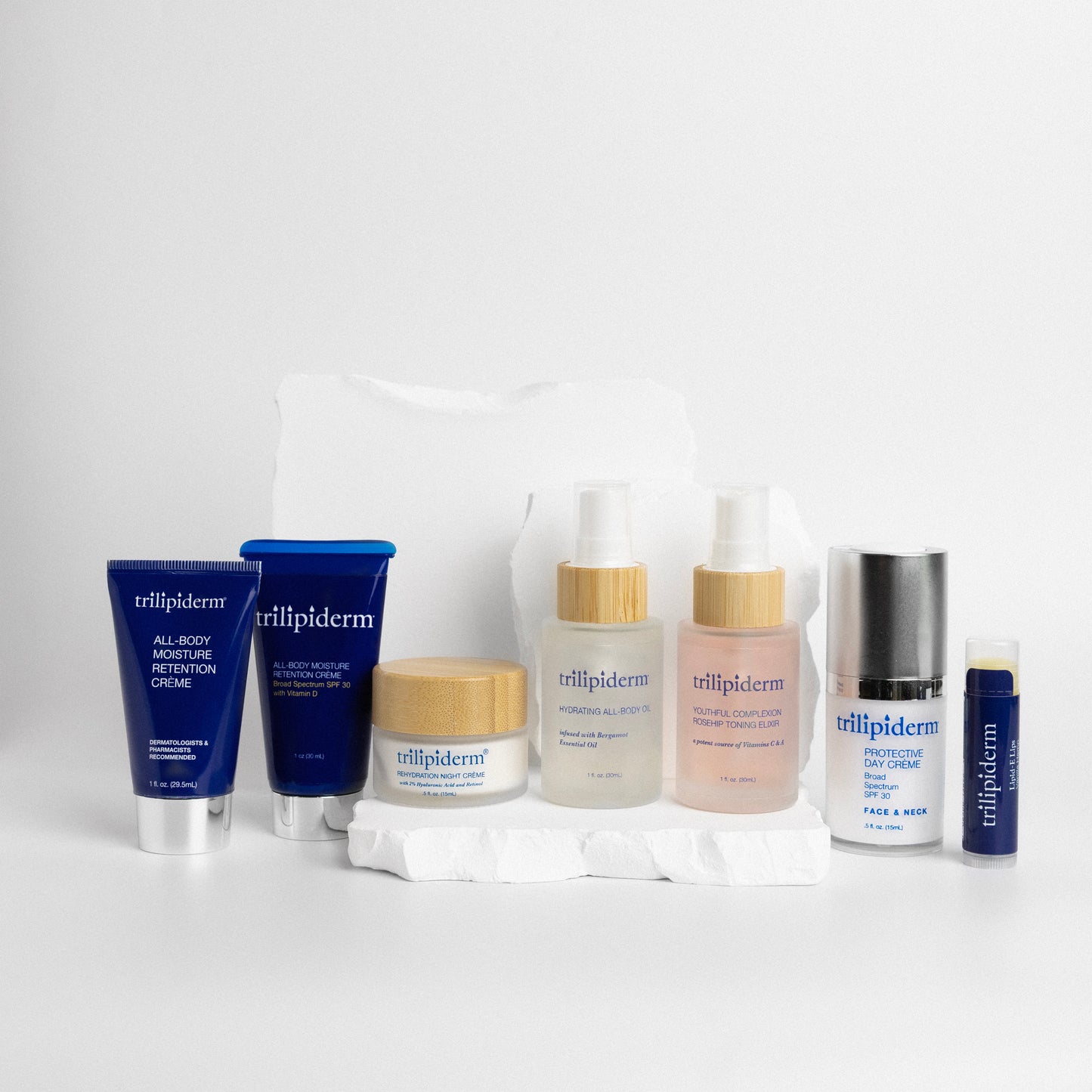 Trillipiderm skincare products on a white background and white rock