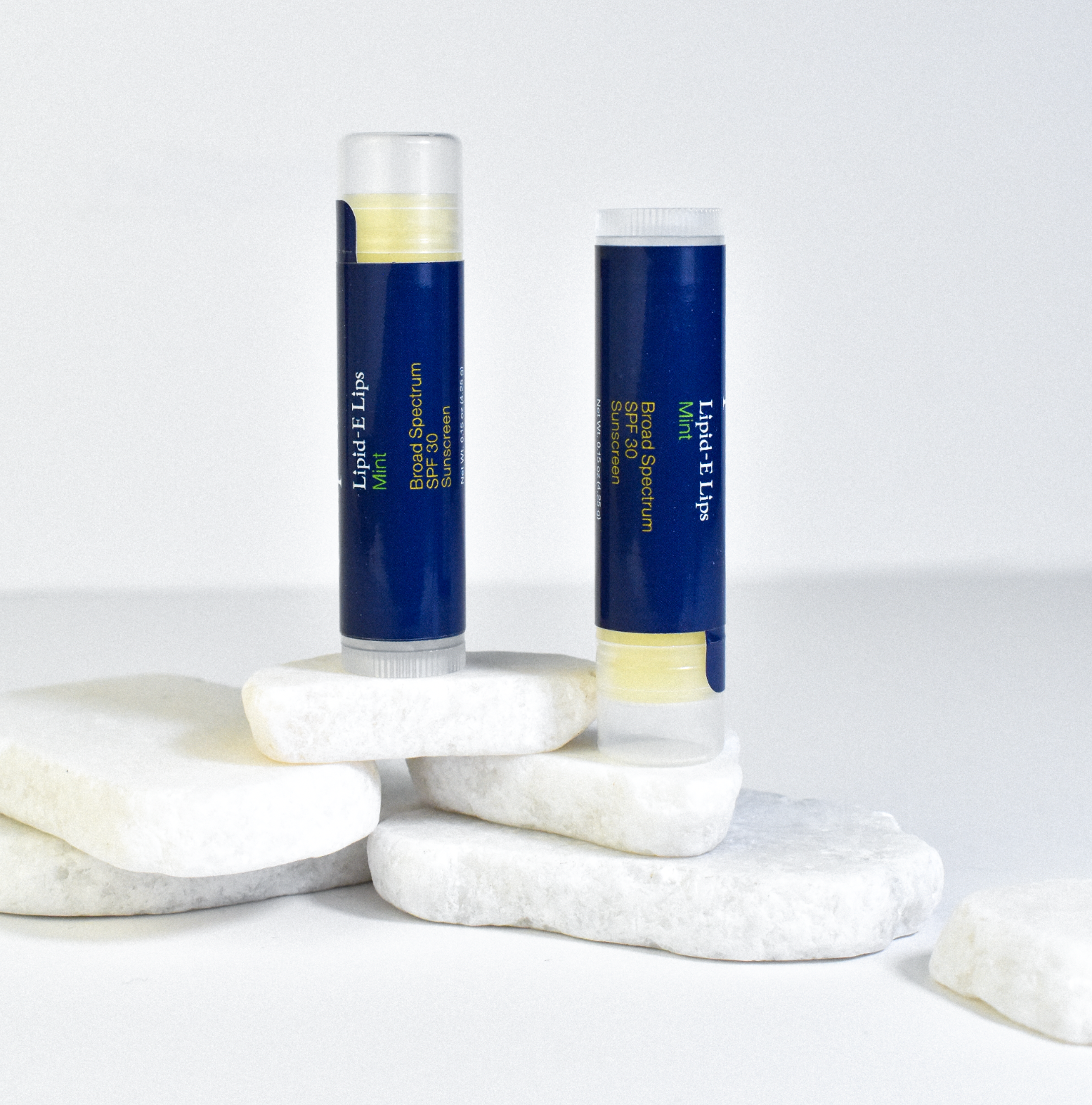 two lip balms displayed on white rock