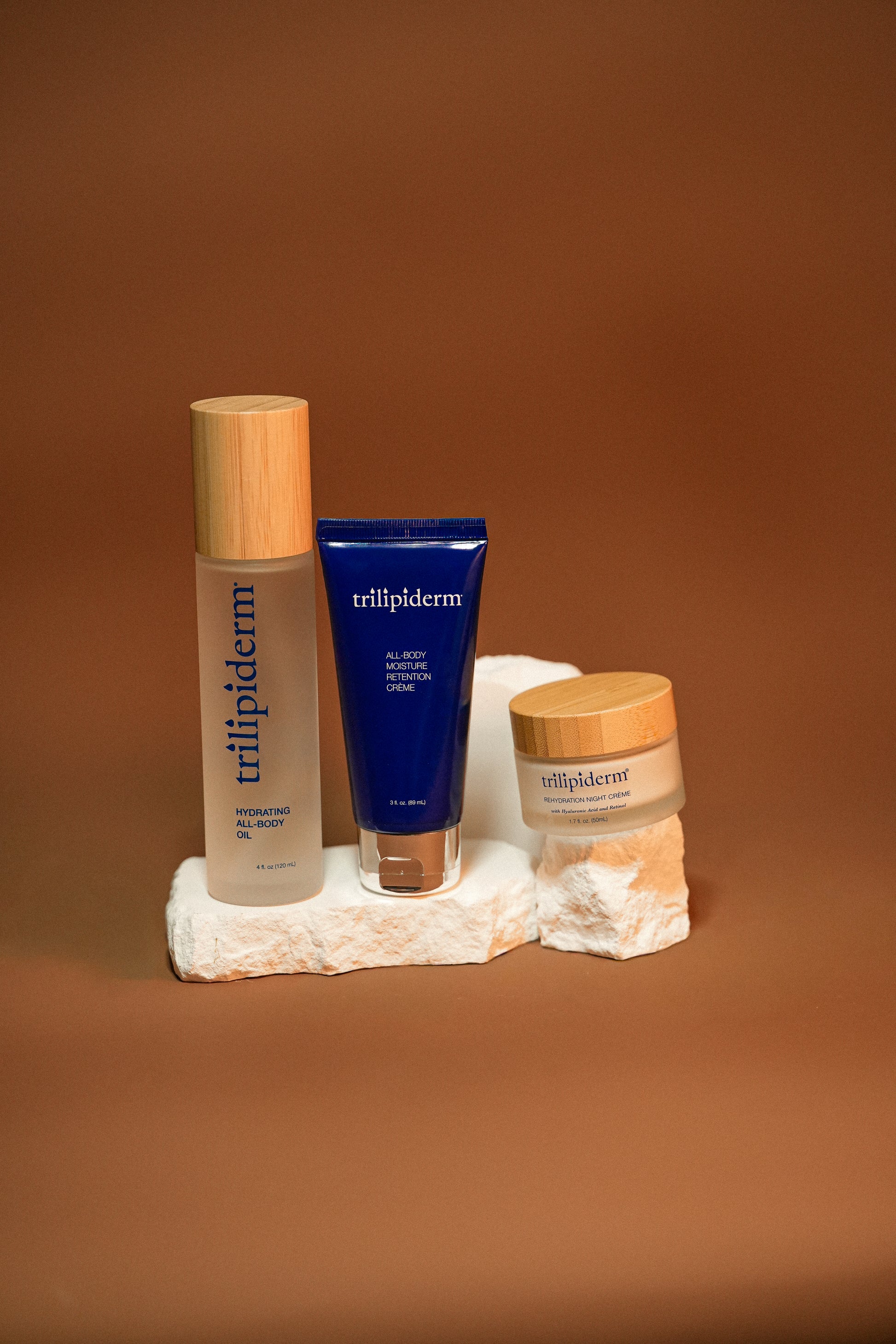 Trilipiderm skincare products on a stone surface with a brown background