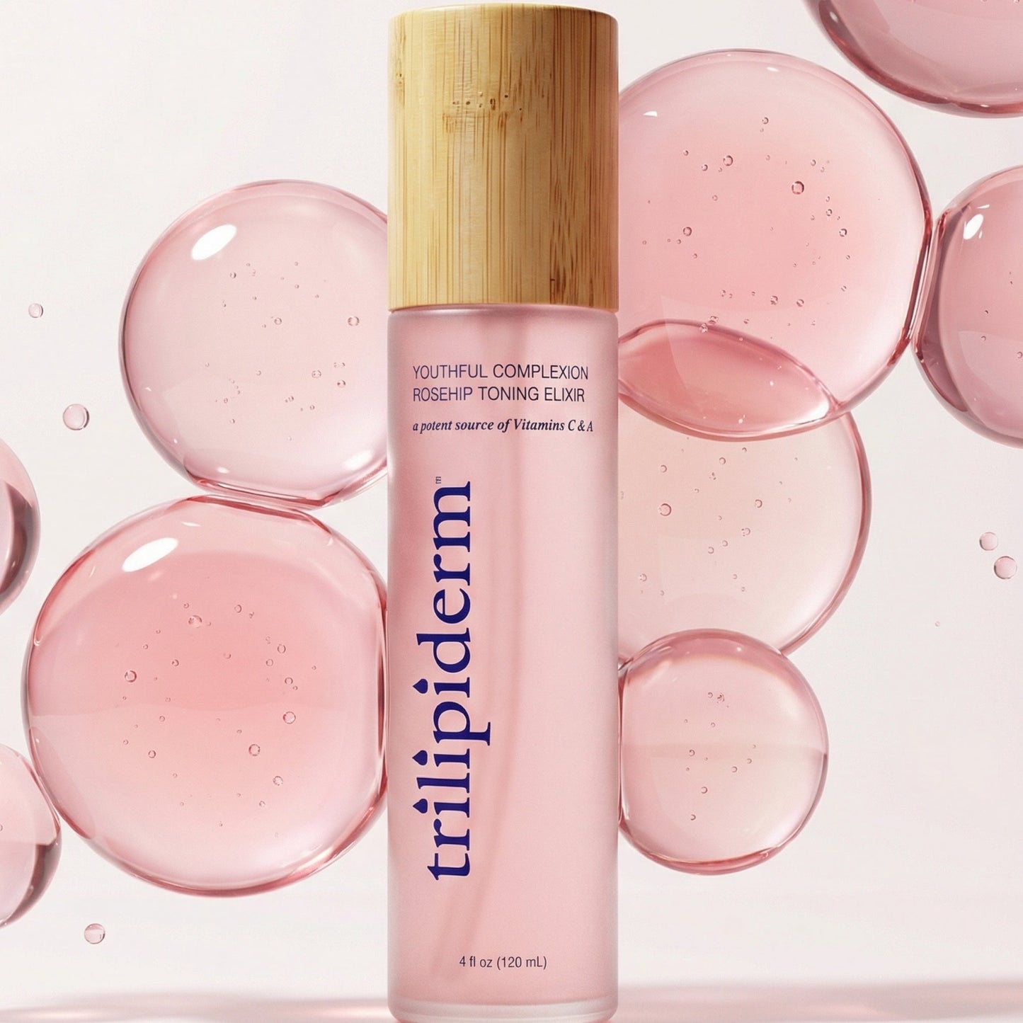 Trilipiderm Youthful Complexion Rosehip Toning Elixir spray toner in a frosted pink bottle with bamboo cap, standing on a glossy surface with translucent pink bubble spheres in the background. Hydrating, antioxidant-rich facial mist toner designed to refresh dull, dehydrated skin, support a healthy-looking glow, and soften the look of texture. Use after cleansing, before serums, or throughout the day over makeup for a dewy, revived finish. Luxury clean skincare aesthetic, minimalist studio lighting, closeup