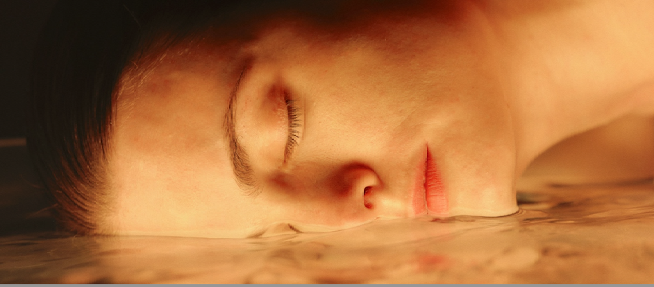 Woman resting with eyes closed on reflective water symbolizing deep skin hydration, glowing complexion, and calming skincare wellness.