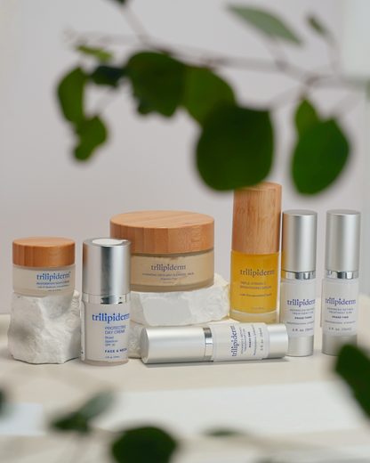 Trillipiderm skincare products on a neutral background with green leaves.