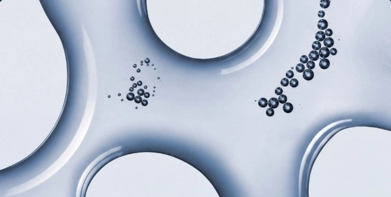 Abstract close-up of a glossy translucent blue surface with circular cutouts and small dark bubble-like droplets.