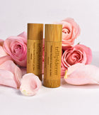 bamboo encased lip balm surrounded by pink flowers with a pink hued background