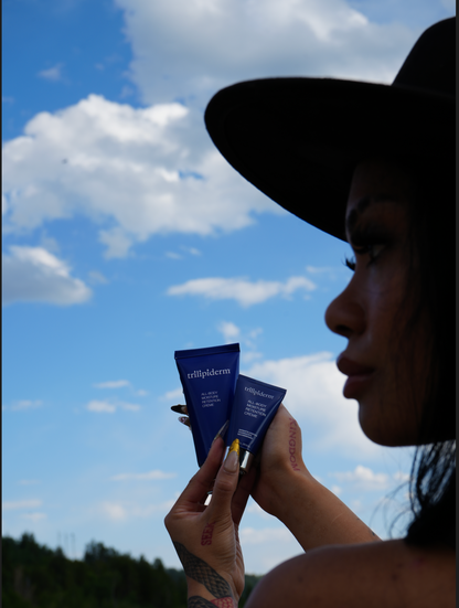Person holding two blue skincare products against a blue sky