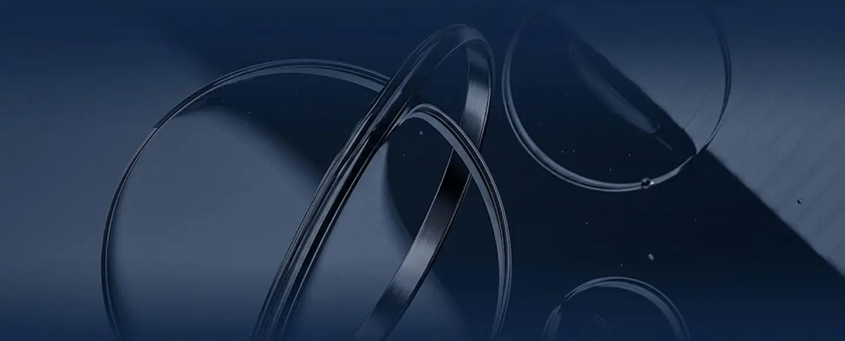 A close-up abstract view of several overlapping transparent circular lens-like rings on a dark blue background.