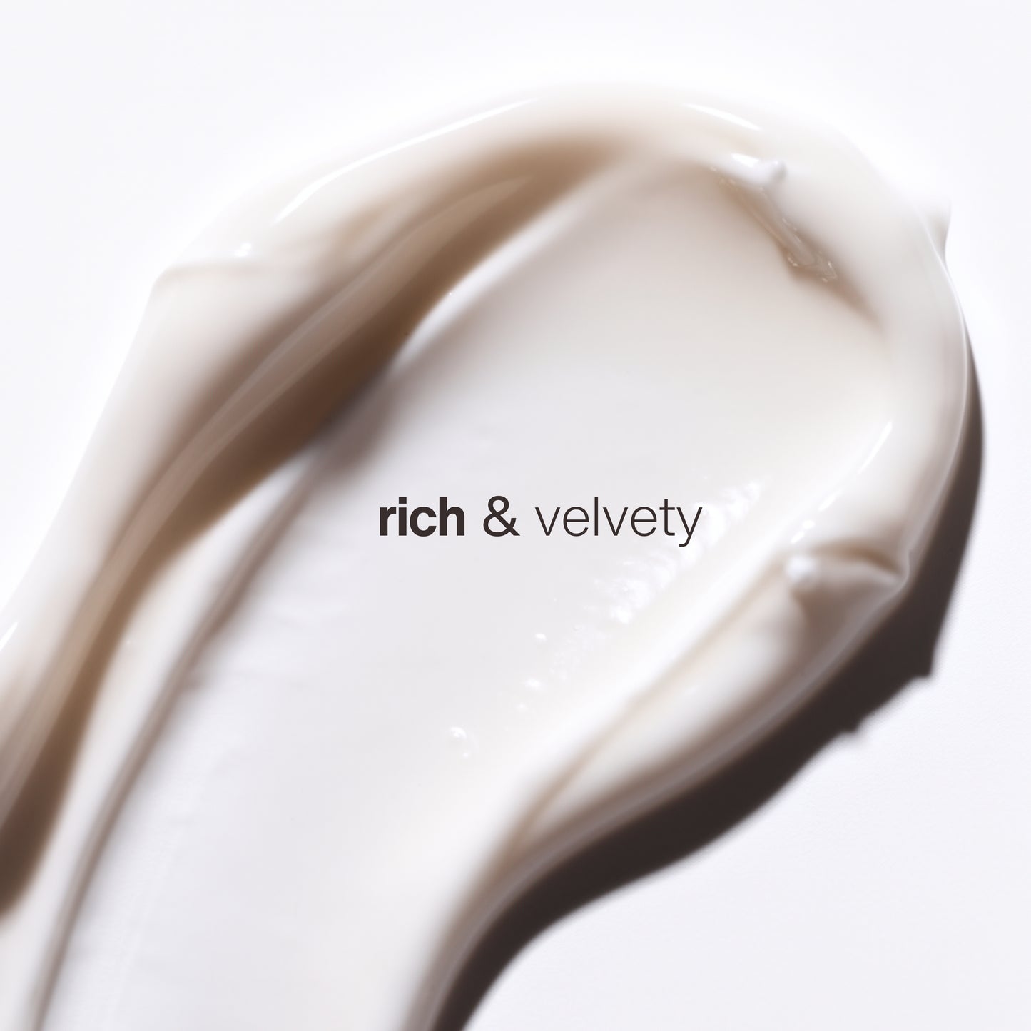 A close-up of a thick, creamy off-white cosmetic smear of rehydration night crème moisturizer with the text 'rich & velvety' printed across the center on a white background. The rich velvety cream is infused with hyaluronic acid and retinol for a smooth hydrating finish.