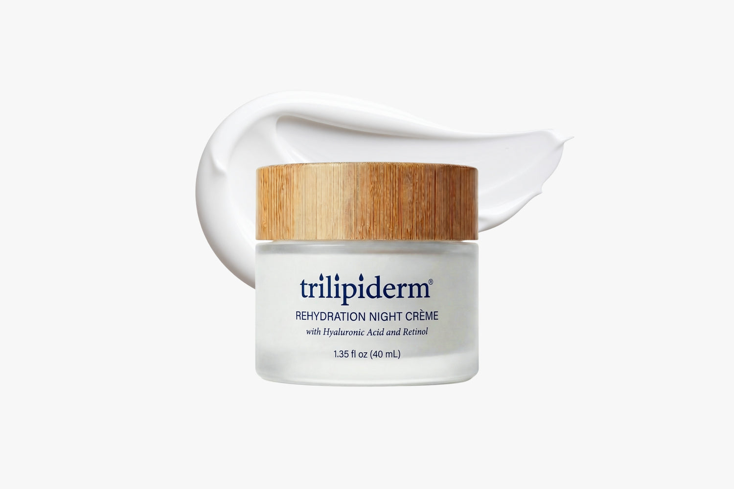 Trilipiderm Rehydration Night Crème in a frosted glass jar with bamboo lid on a clean white background, styled with a silky cream swatch behind it. Rich, velvety overnight moisturizer featuring hyaluronic acid and retinol for a smooth, hydrated glow.