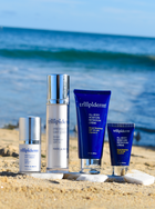 A beach setting with Trilipiderm sun protection products including a tube, bottle, and box of sunscreen, and a bottle of moisture retention cream.