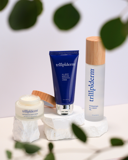 Trillipiderm skincare products on a white surface with green leaves in the background