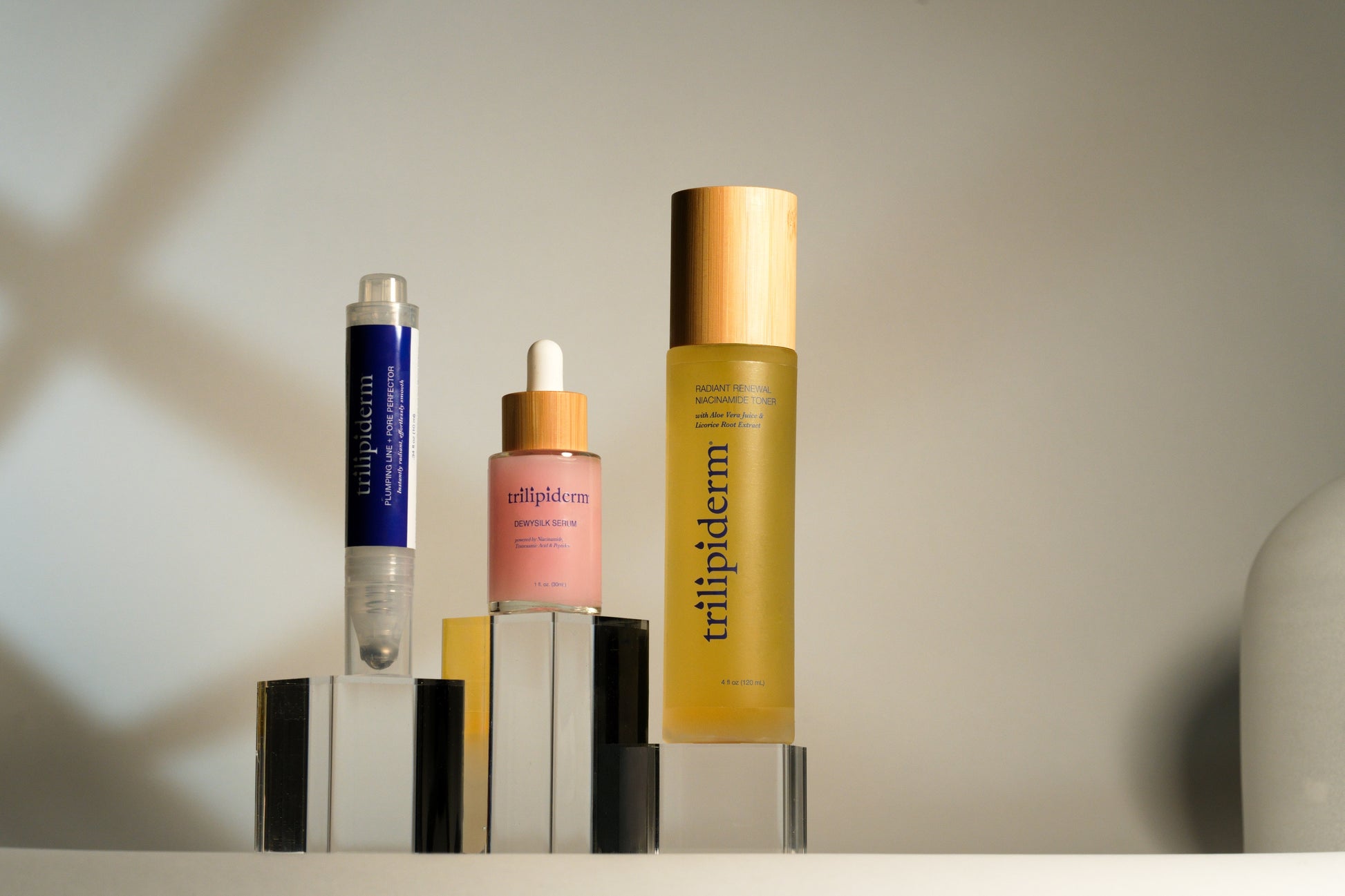 Trilipiderm Beauty in Balance Bundle displayed in natural lighting with Niacinamide Toner, DewySilk Serum, and Plumping Line + Pore Perfector for a refined, brightening skincare routine.