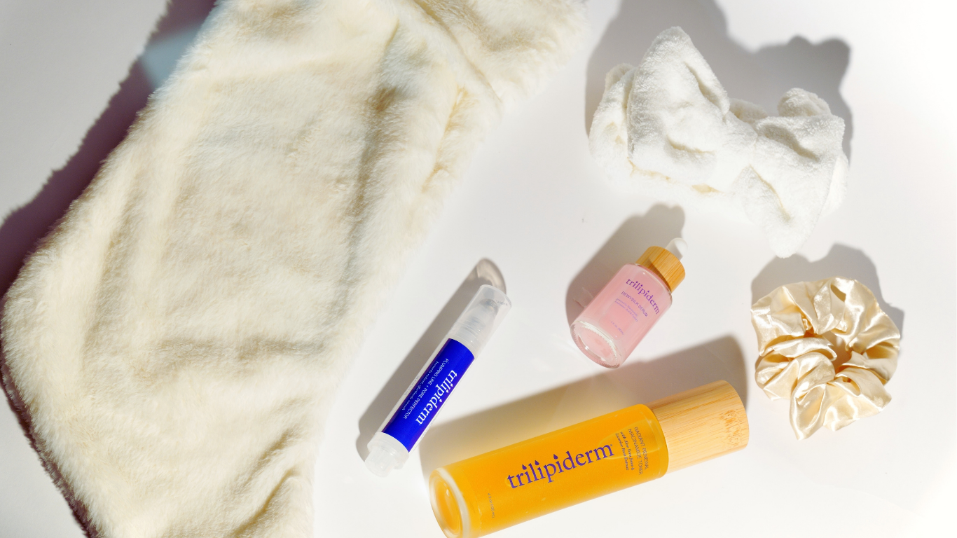 Flat lay of the Trilipiderm Beauty in Balance holiday skincare set featuring DewySilk Serum, Plumping Line & Pore Perfector, Radiant Renewal Niacinamide Toner, satin scrunchie, plush headband, and faux-fur pouch — luxury winter skincare from Jackson Hole