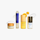 Trilipiderm plumping perfector, lifting eye crème, vitamin C serum, and protective day crème displayed on acrylic blocks in warm light