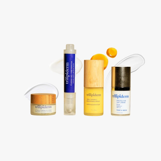 Trilipiderm plumping perfector, lifting eye crème, vitamin C serum, and protective day crème displayed on acrylic blocks in warm light
