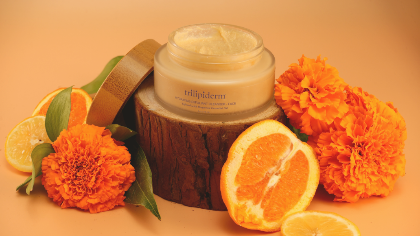 Trilipiderm Hydrating Exfoliant Cleanser with bergamot essential oil surrounded by oranges and marigolds