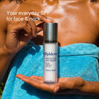 A person wrapped in a bright blue towel holds a bottle of Trilipderm Protective Day Crème SPF 30 sunscreen. White text on the image reads 'Your everyday SPF for face & neck'.