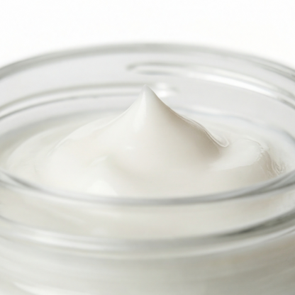 Close-up of Trilipiderm Rehydration Night Crème texture in a clear glass jar, showing a smooth, velvety peak of cream with a soft glossy finish—rich overnight moisturizer with hyaluronic acid and retinol.