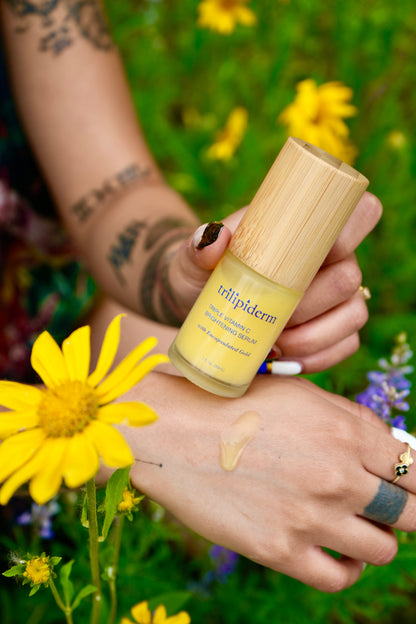 Person holding a bottle of 'trillipiderm' product with flowers in the background